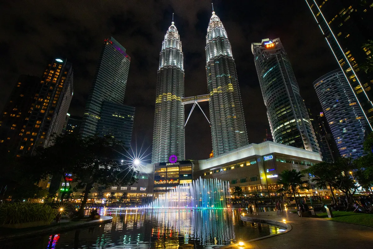 The Petronas Twin Towers lit up at night above the KLCC fountain